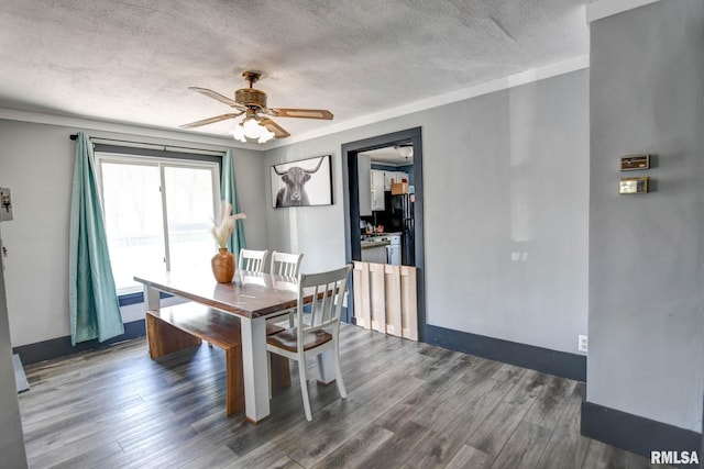 dining room featuring wood finished floors, a textured ceiling, baseboards, and ceiling fan