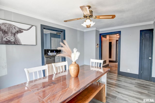 dining space featuring light wood-style flooring, baseboards, a ceiling fan, and crown molding