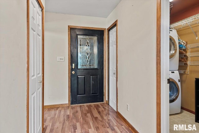 foyer with stacked washing maching and dryer, wood finished floors, and baseboards
