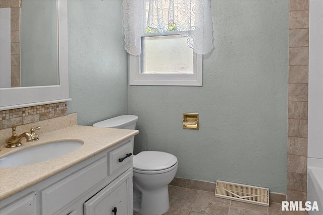 bathroom with a textured wall, visible vents, toilet, a bath, and vanity