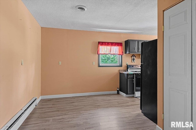 kitchen featuring freestanding refrigerator, baseboard heating, gas stove, visible vents, and a textured ceiling