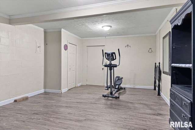 exercise area with wood finished floors, concrete block wall, and a textured ceiling