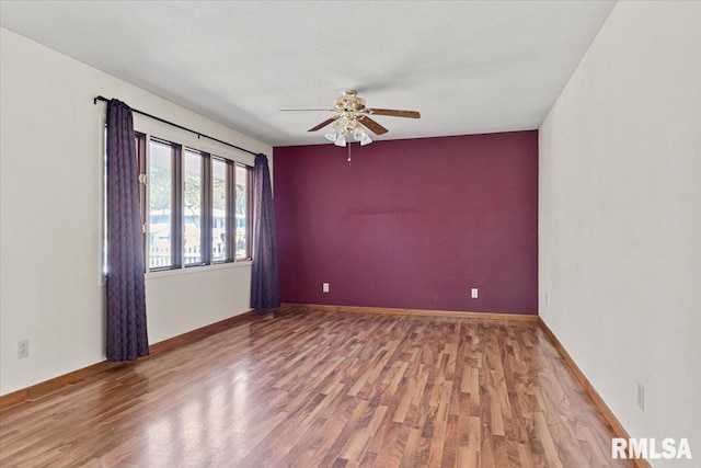 spare room with ceiling fan, wood finished floors, and baseboards