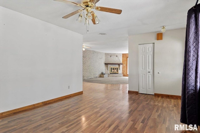 unfurnished living room featuring a ceiling fan, wallpapered walls, wood finished floors, and baseboards