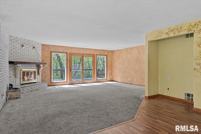 unfurnished living room with a fireplace, wood finished floors, visible vents, and baseboards