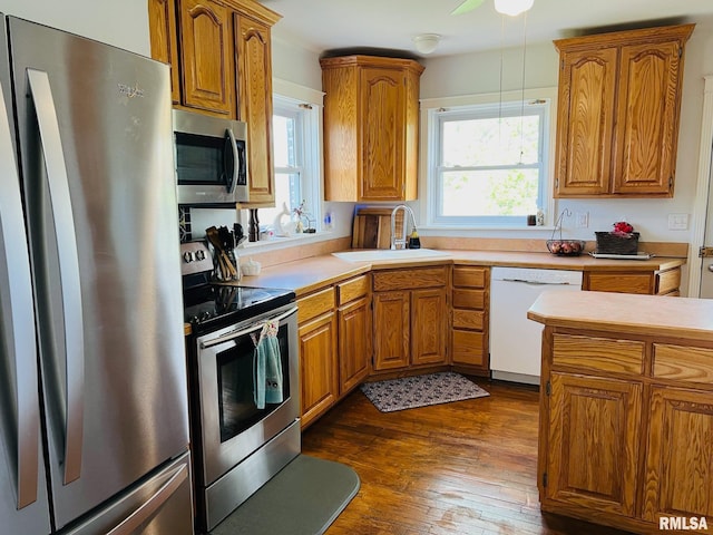 kitchen with brown cabinetry, stainless steel appliances, and a sink