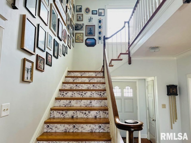 stairs with a high ceiling, crown molding, and baseboards