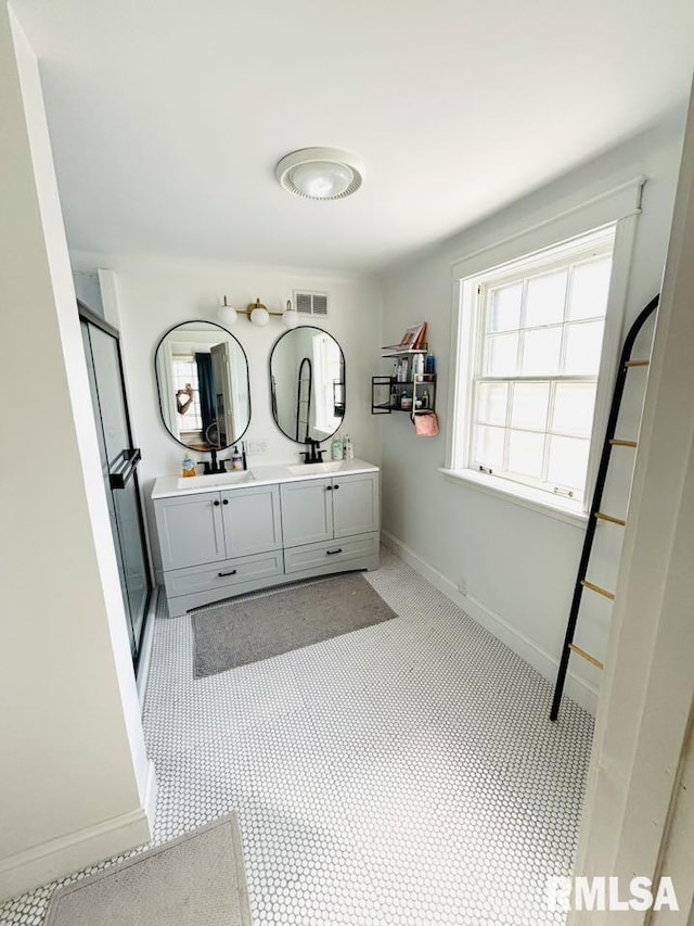 bathroom with baseboards, double vanity, and visible vents