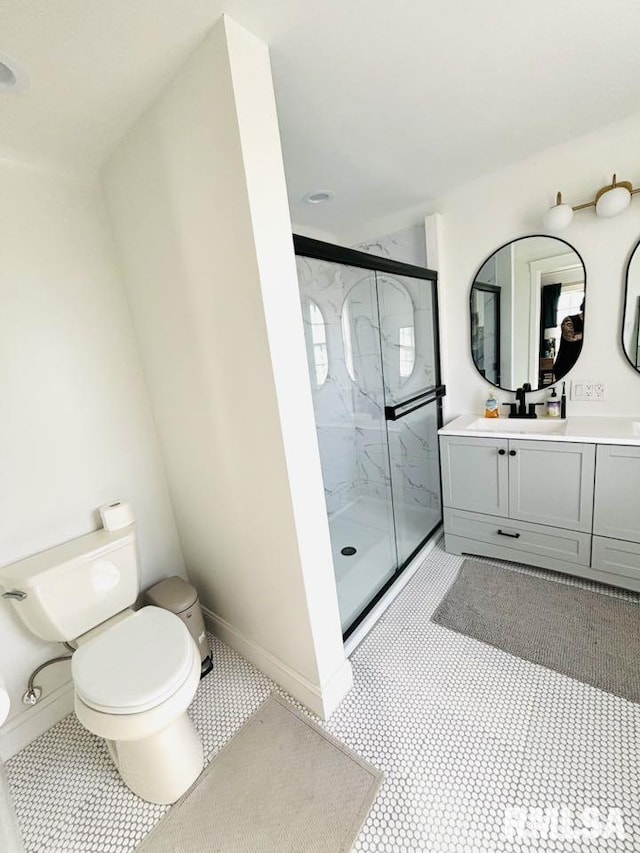 bathroom with baseboards, a marble finish shower, vanity, and toilet