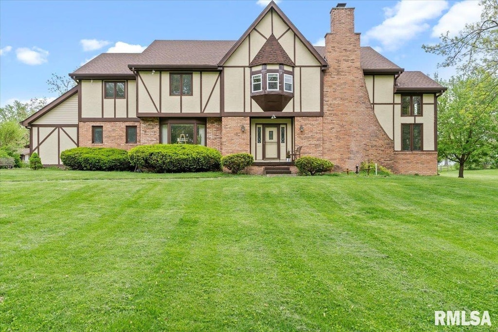 view of front of house featuring a chimney, stucco siding, and brick siding