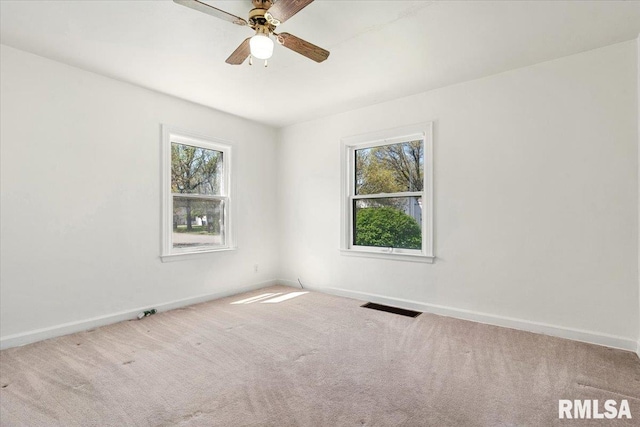 carpeted spare room featuring visible vents, baseboards, and a healthy amount of sunlight