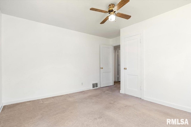 spare room featuring light carpet, a ceiling fan, visible vents, and baseboards