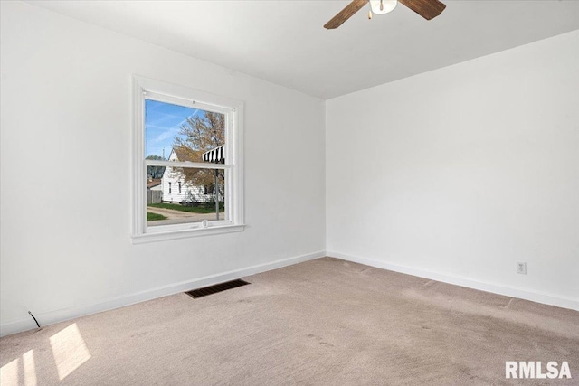 spare room with carpet flooring, visible vents, a ceiling fan, and baseboards