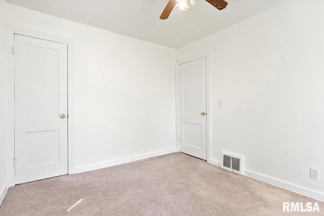 carpeted spare room featuring baseboards, a ceiling fan, and visible vents