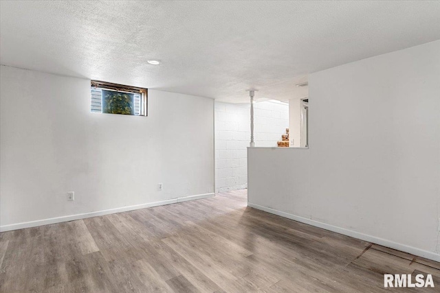 basement featuring baseboards, wood finished floors, and a textured ceiling