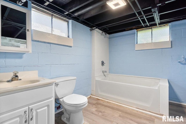 bathroom featuring a wealth of natural light, toilet, bathtub / shower combination, wood finished floors, and vanity