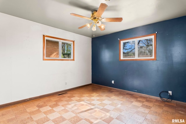 empty room featuring baseboards, a ceiling fan, and visible vents