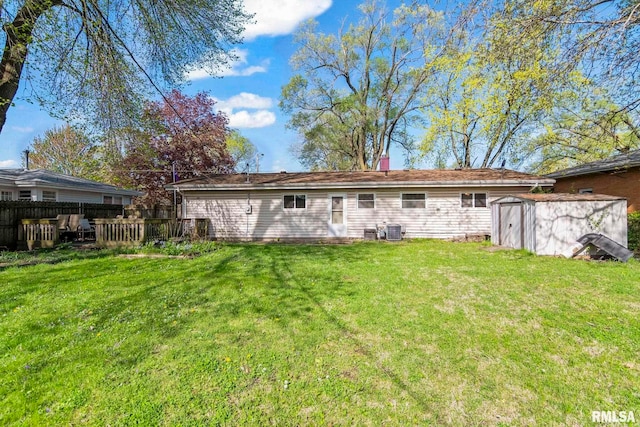rear view of house featuring a storage shed, a lawn, fence, and an outdoor structure