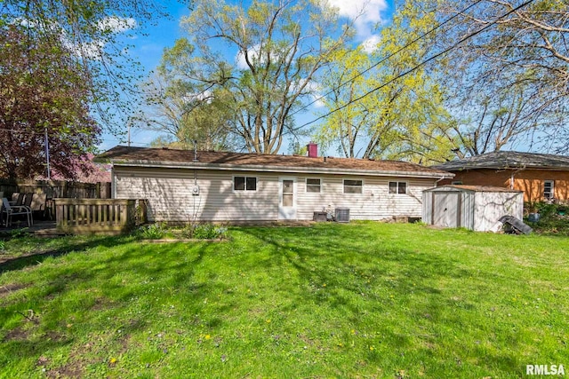 rear view of property featuring a storage shed, an outbuilding, central AC, a chimney, and a lawn