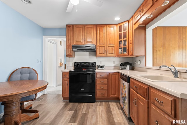 kitchen with brown cabinetry, black range with electric stovetop, dishwasher, a sink, and under cabinet range hood