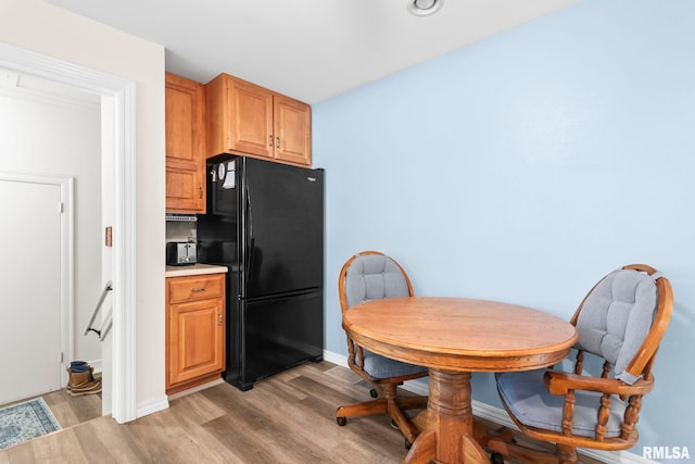 kitchen with freestanding refrigerator, baseboards, light wood-style flooring, and light countertops