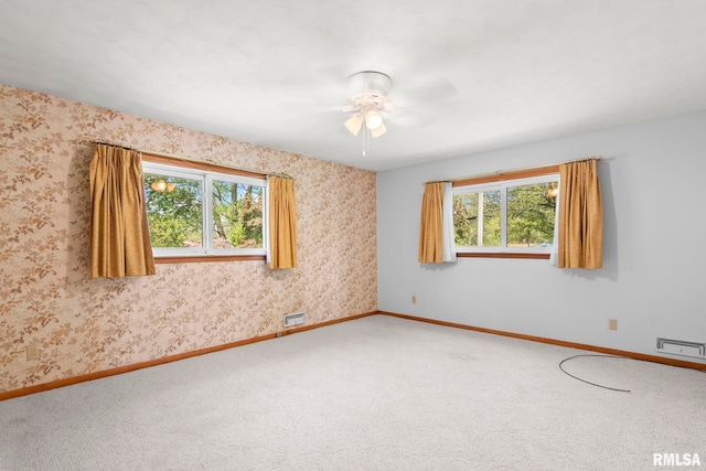 unfurnished room with baseboards, carpet flooring, ceiling fan, and a wealth of natural light