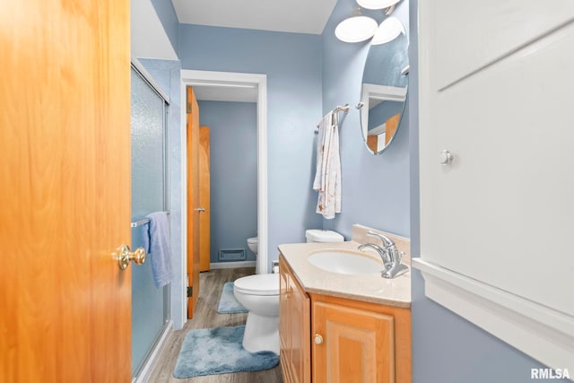 full bathroom featuring vanity, toilet, wood finished floors, and a stall shower