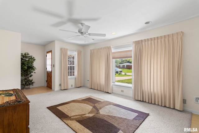 unfurnished bedroom with light colored carpet, a ceiling fan, and baseboards