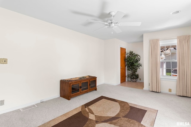 carpeted spare room with visible vents, baseboards, and ceiling fan