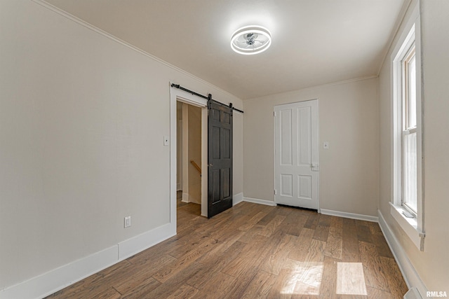 203 Oglesby Ave, Lincoln, IL 62656 - unfurnished bedroom with crown molding, baseboards, dark wood-style floors, and a barn door