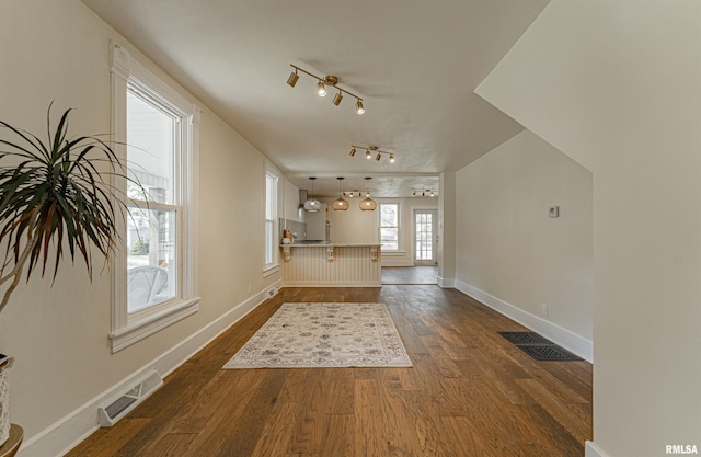 203 Oglesby Ave, Lincoln, IL 62656 - unfurnished living room featuring baseboards, visible vents, rail lighting, and dark wood-type flooring