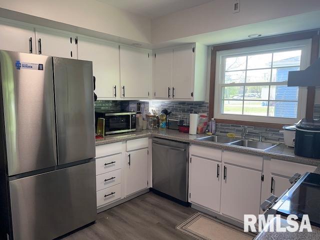 kitchen featuring white cabinets, stainless steel appliances, a sink, and backsplash