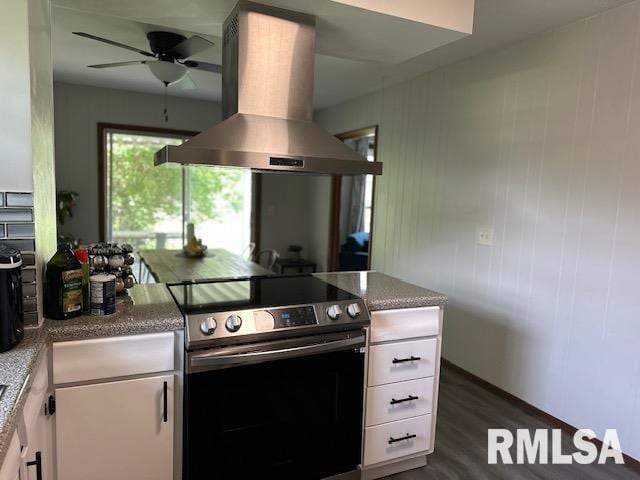 kitchen with white cabinets, island range hood, a ceiling fan, stainless steel electric range, and dark wood-style flooring
