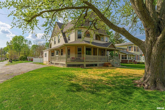 victorian-style house featuring aphalt driveway, a front yard, and a porch