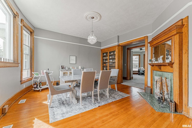 dining space featuring light wood-type flooring, plenty of natural light, a notable chandelier, and a fireplace