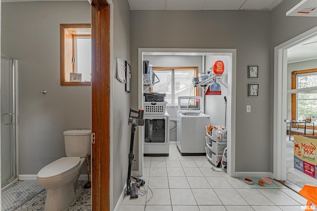 bathroom featuring independent washer and dryer, tile patterned floors, toilet, baseboards, and a drop ceiling