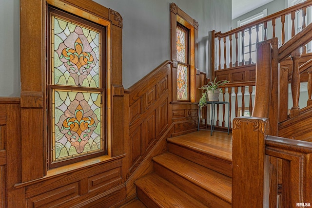 stairs featuring wainscoting and a decorative wall