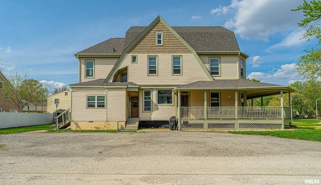 view of front of home with a shingled roof, covered porch, and fence