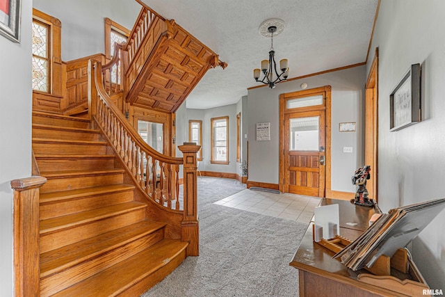 entrance foyer featuring a chandelier, light tile patterned flooring, baseboards, a textured ceiling, and light colored carpet