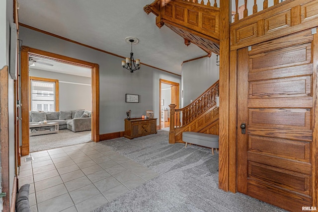 entryway with light tile patterned floors, crown molding, light colored carpet, baseboards, and stairs