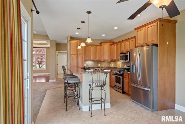 kitchen with recessed lighting, dark stone counters, decorative backsplash, stainless steel appliances, and a kitchen bar