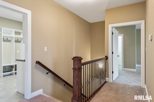 corridor with an upstairs landing, carpet floors, and baseboards