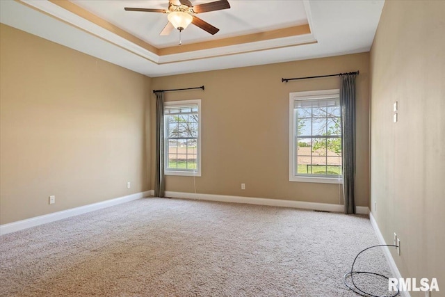 empty room featuring light colored carpet, a ceiling fan, and a tray ceiling