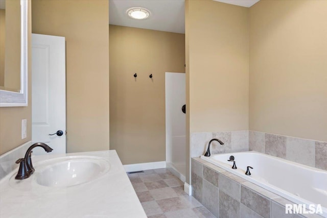 full bathroom with a bath, vanity, and baseboards