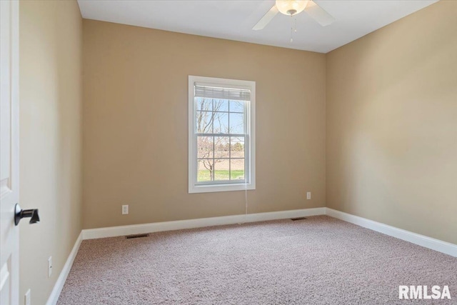 carpeted empty room with baseboards, visible vents, and a ceiling fan
