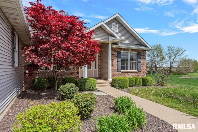 view of front facade with brick siding and a front yard