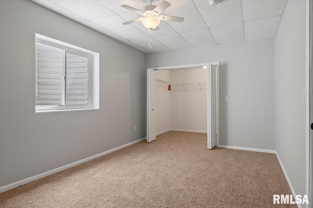 unfurnished bedroom featuring baseboards, carpet floors, a closet, and a paneled ceiling