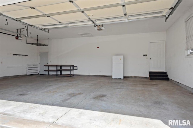 garage with a garage door opener and freestanding refrigerator