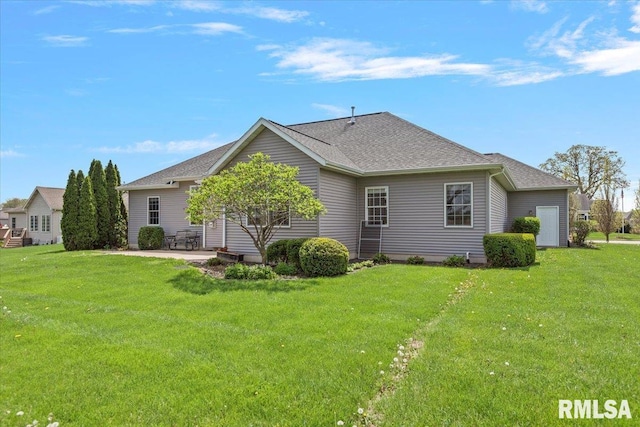 back of house featuring roof with shingles, a yard, and a patio