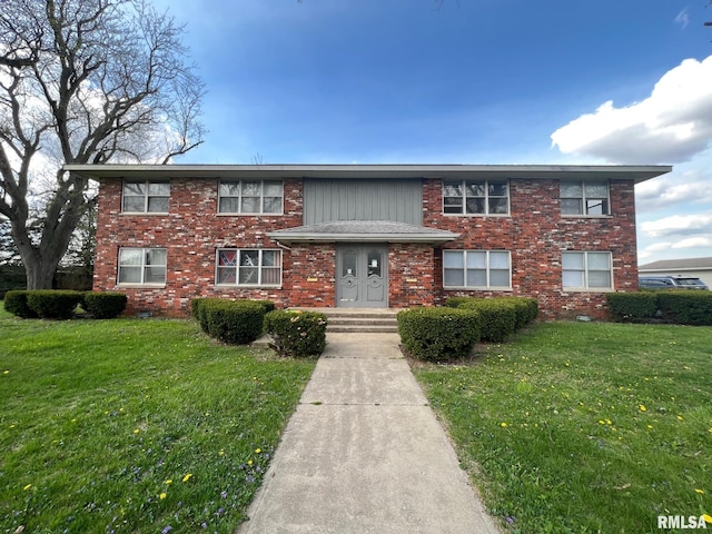 view of front facade with brick siding and a front lawn
